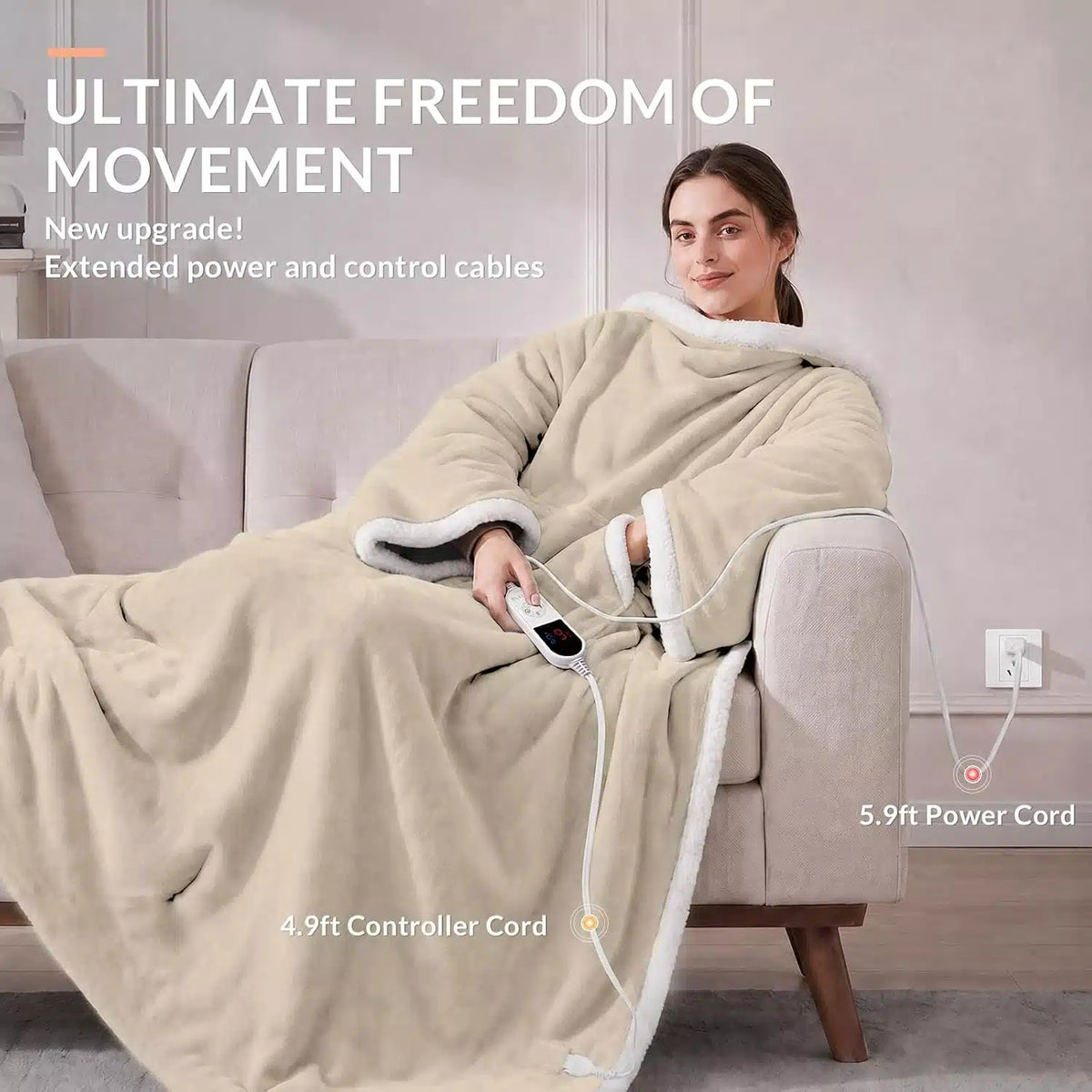 A woman reclines on a sofa wearing a beige plush heated wearable blankets. The blanket has a hood and the woman holds a white controller.
